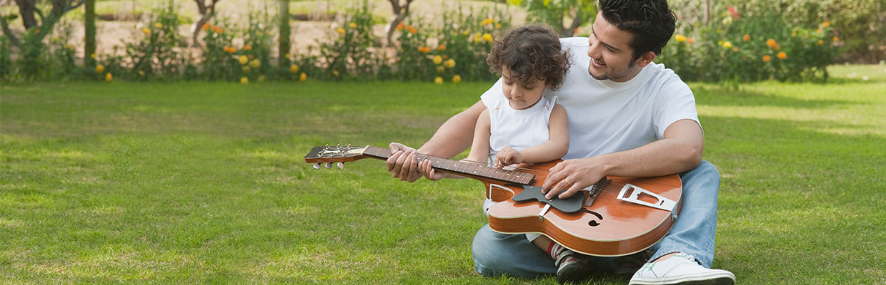 A father is teaching his kid playing guitar; image used for HSBC NRE rupee term deposit.