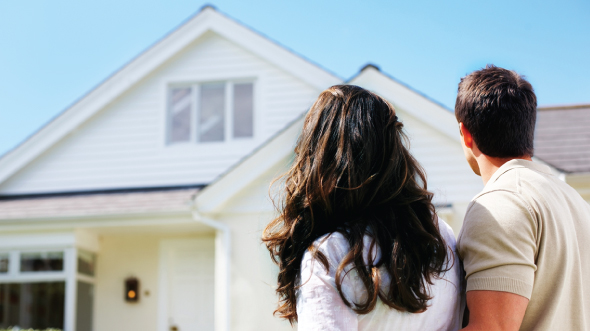 A couple stand in front of a house; image used for HSBC Goal planning page.