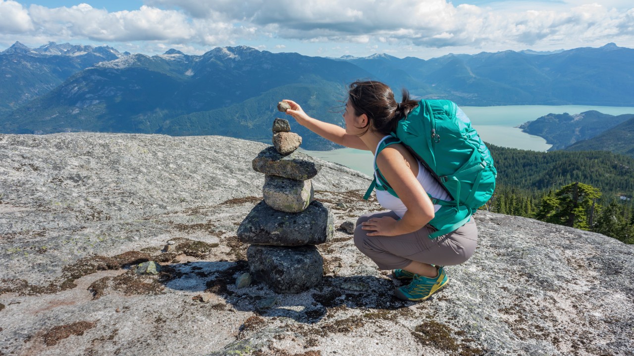 A backpacker stacking rocks; image used for HSBC foreign exchange rates page.