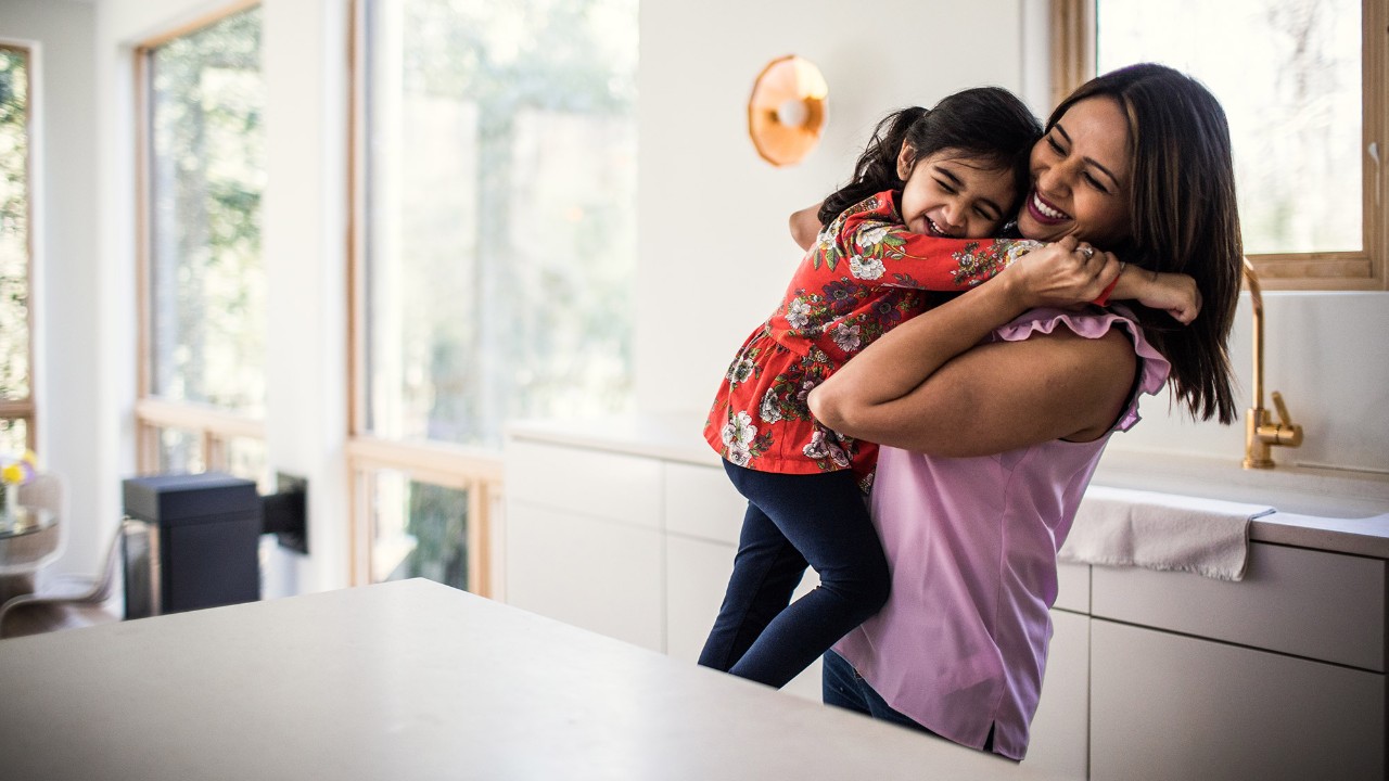A girl is cuddling to her mom; image used for HSBC India wealth insight page.