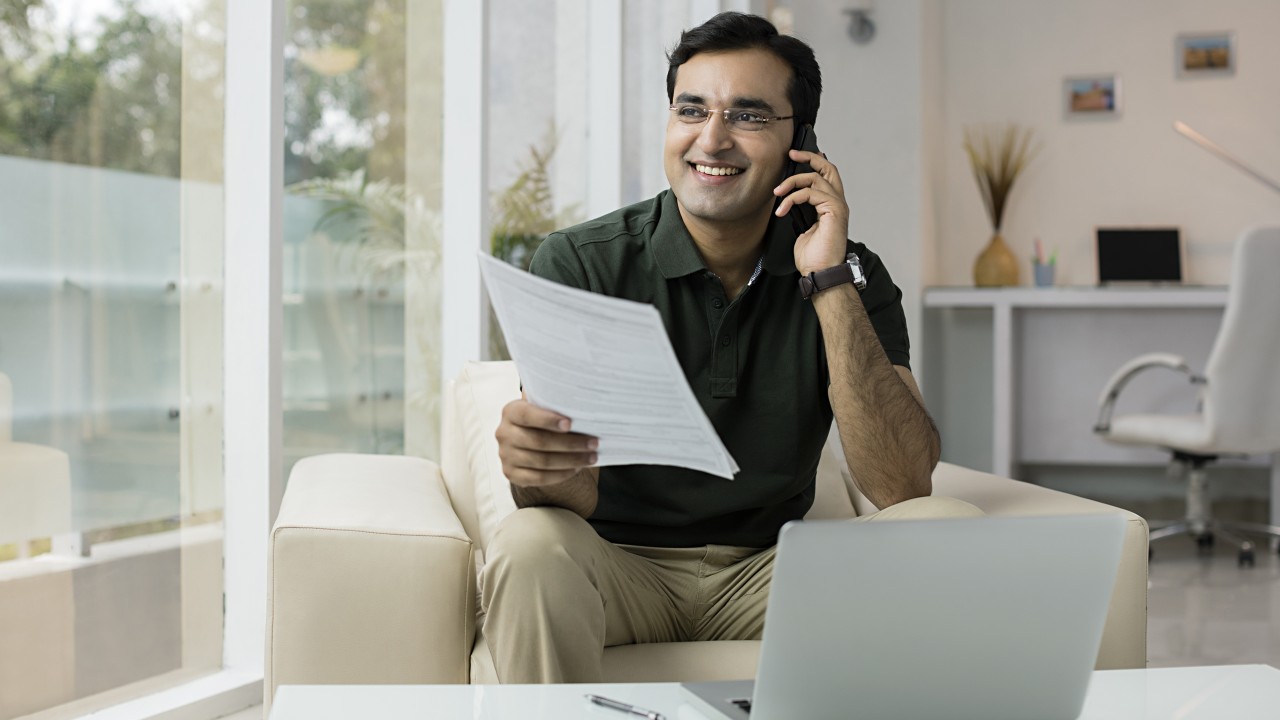A man holding document and talking over the phone happily; image used for HSBC NRE rupee account page