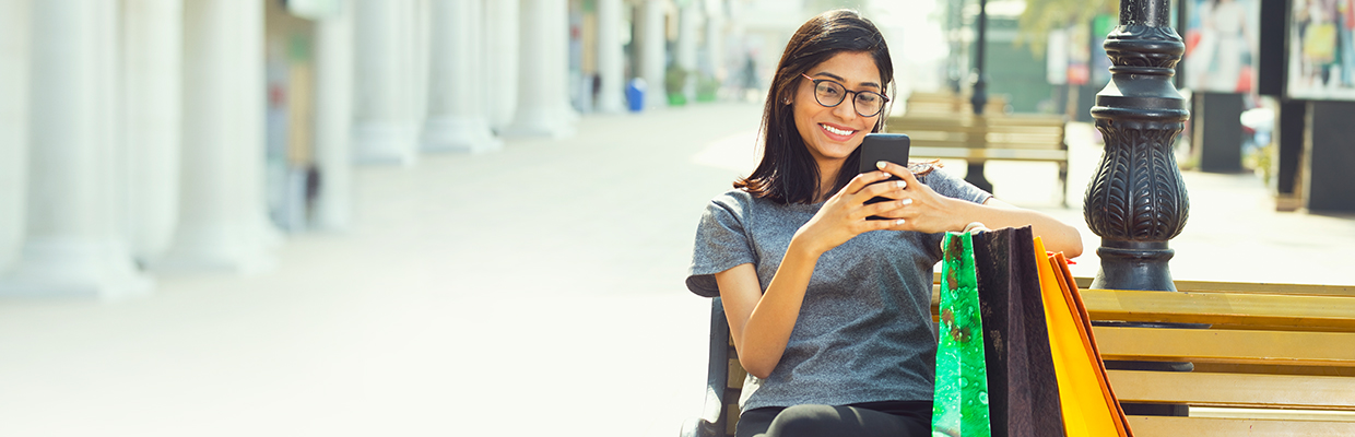 A woman sitting on bench and playing with her mobile phone; image used for HSBC Balance Conversion.
