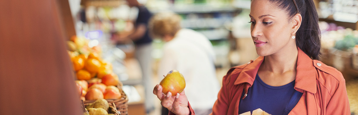 A woman shopping for some apples; image used for HSBC compare NRI services page.