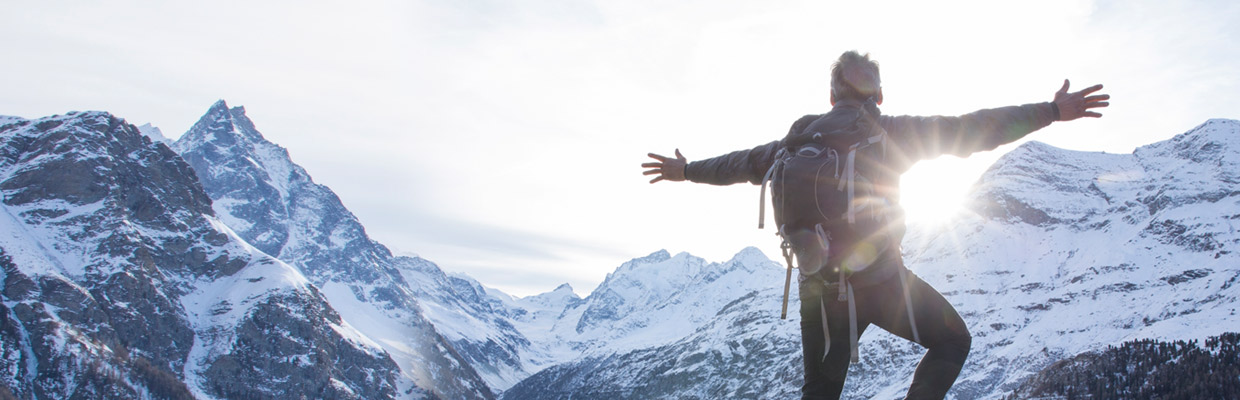 A man standing on mountain summit with arms outstretched; image used for HSBC Credit Card Features.