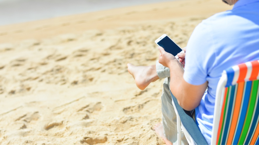 Man using phone at beach; image used for HSBC India Mobile Banking app