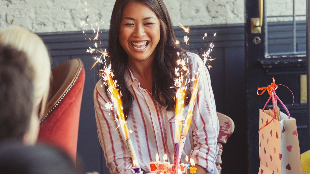 A lady is smiling in front of her birthday candles; image used for HSBC India Fixed Deposit page.