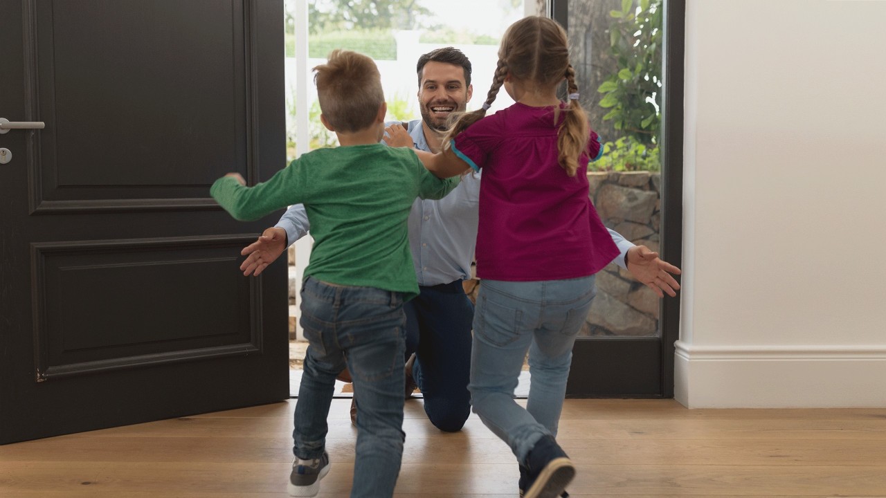 Two kids welcoming father back home with hug; image used for HSBC India Akbar Travels credit card offer page