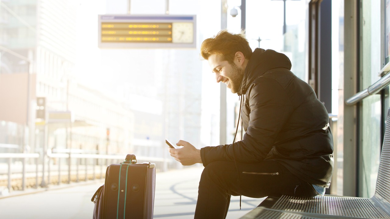 A man using mobile phone at bus station; image used for HSBC India bill payments page.