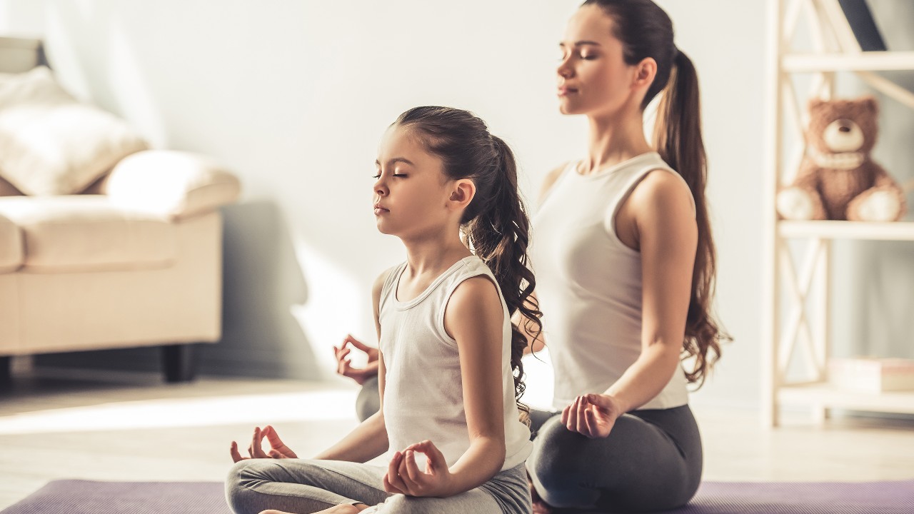 Mom and young girl doing yoga at home; image used for HSBC India Visa cards offers