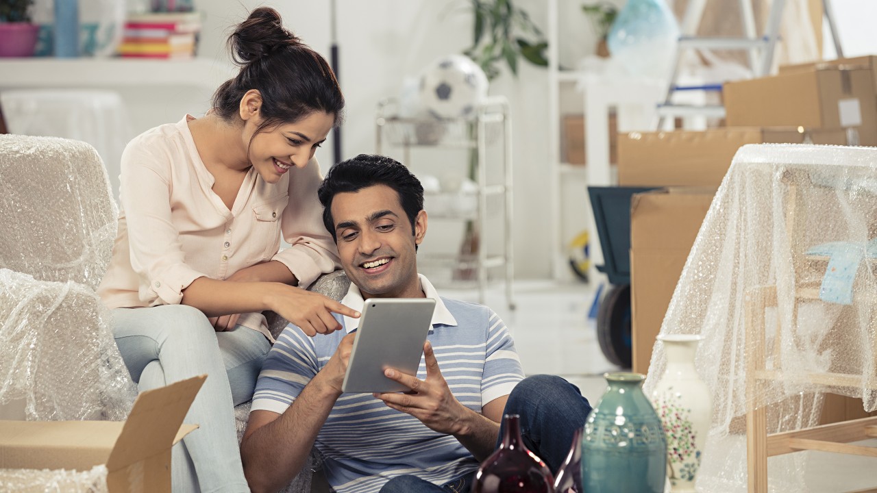 A couple is using tablet together happily at home; image used for HSBC NRO rupee account page