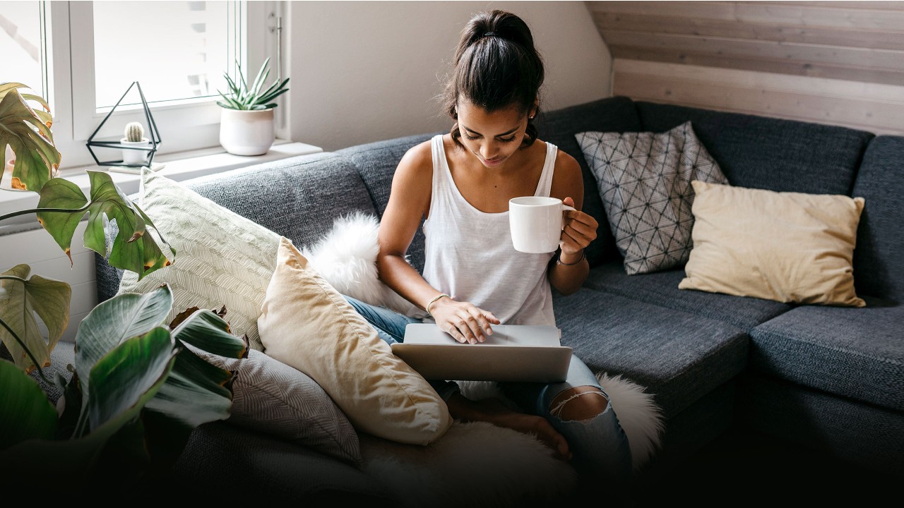 A woman using laptop with a coffee at home; image used for HSBC e-NACH