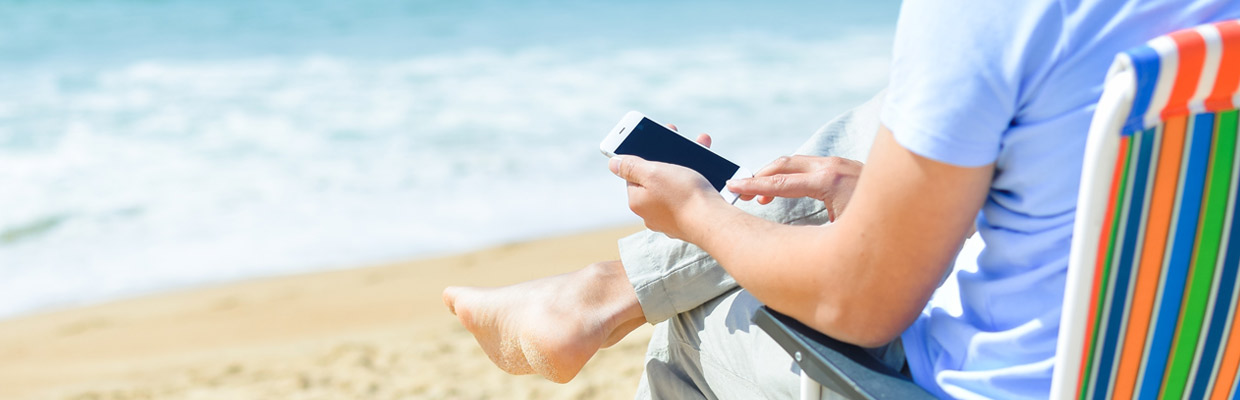 Man using phone at beach; image used for HSBC India Mobile Banking app