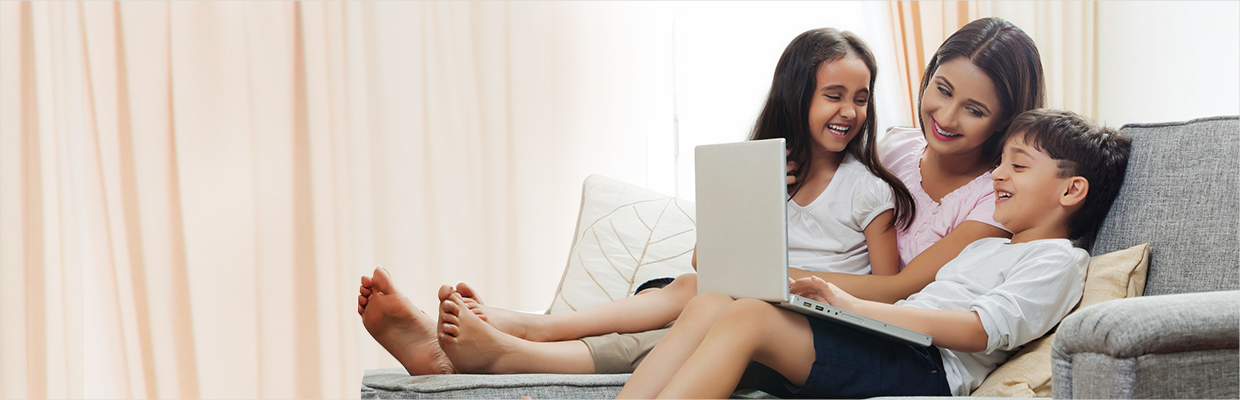 Mom and two kids happily using laptop on sofa; image used for HSBC India credit cards online offers