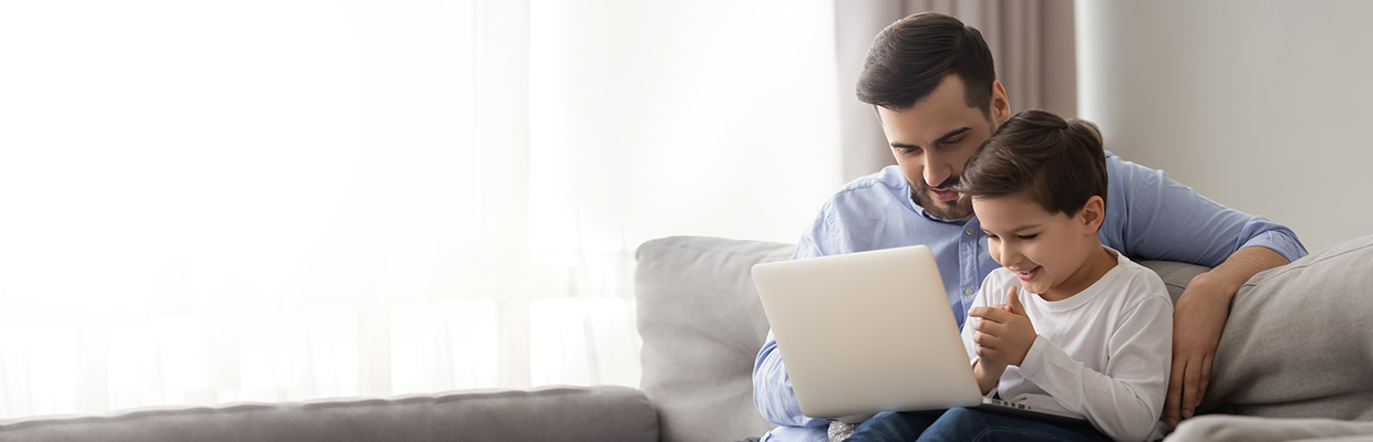 Father and son using laptop on the sofa; image used for HSBC India Instant EMI