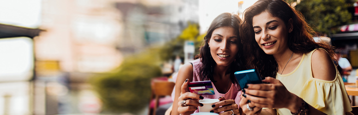 Two women at a cafe with a phone and a credit card; image used for HSBC Cashback Credit Card article page.