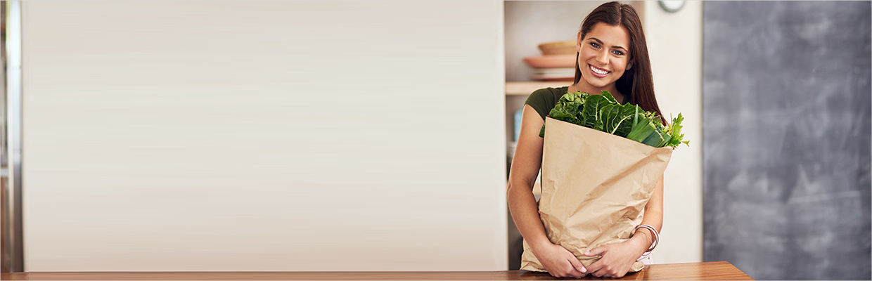 A woman holding a bag of vegetables in front of a table; image used for HSBC Grofers offer