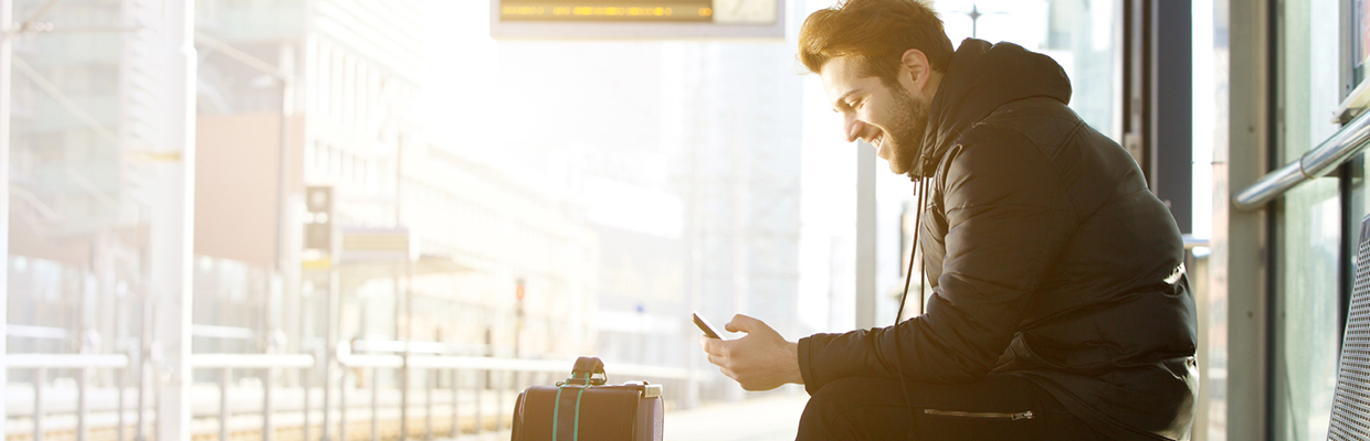 A man using mobile phone at bus station; image used for HSBC India bill payments page