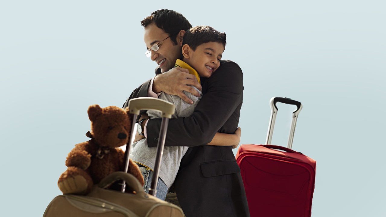 Father and son cuddling near luggage; image used for HSBC India Indigo credit card offer