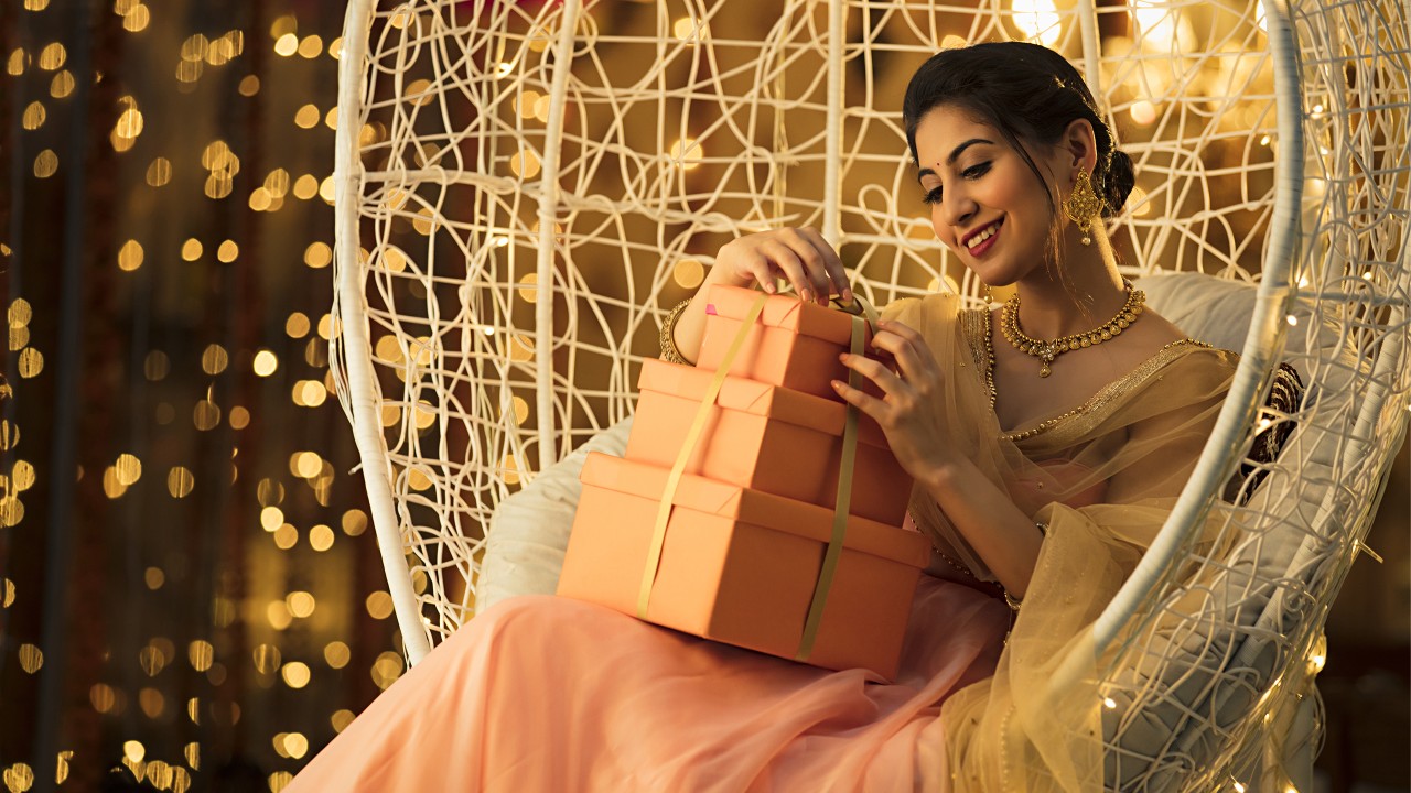 A woman smiles at the gift on hands on the cradle; image used for HSBC India Kalyan Jewellers credit card offer