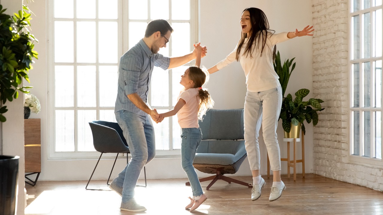 Man, woman and child jumping with joy in living room; image used for HSBC India Titanium Plus life insurance