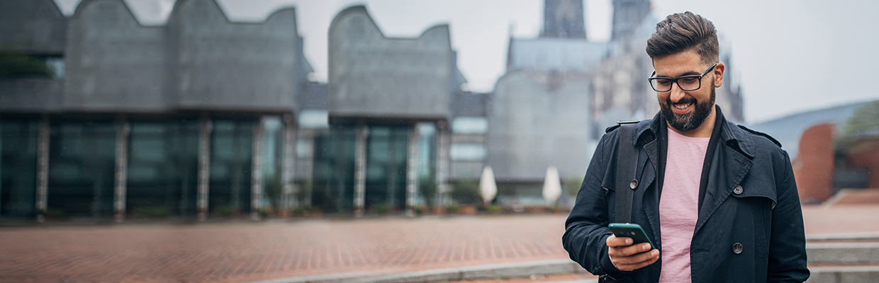 A business man smiling confidently near a bridge; image used for NRI page