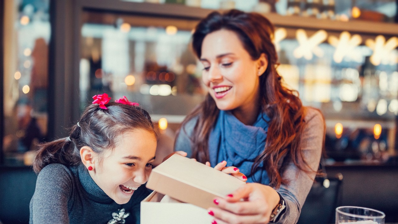 Woman opening gift box in front of female child; image used for HSBC Fixed Deposit.