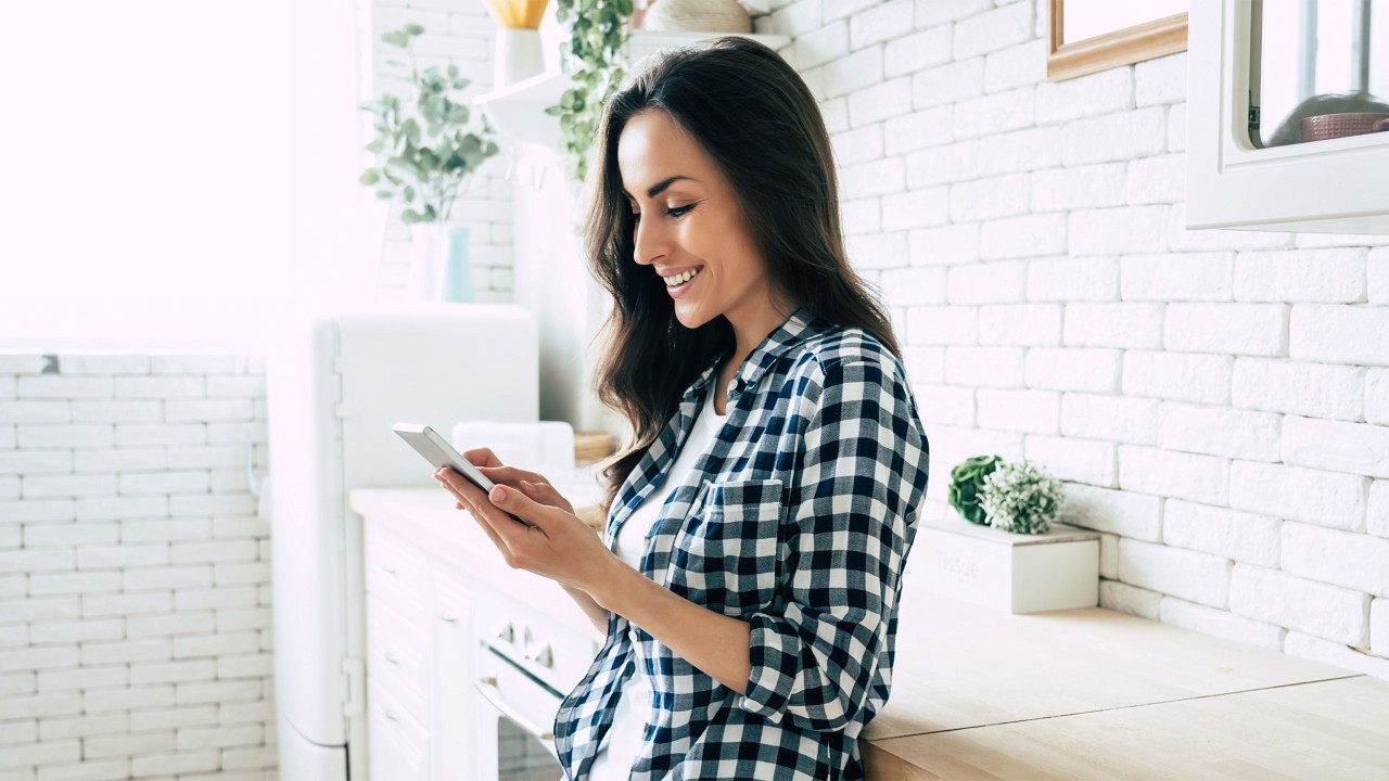 A woman using mobile in the kitchen