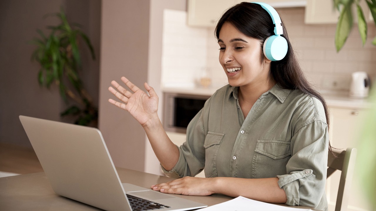 A woman with headphone in front of laptop; image used for HSBC India Video Customer Identification Process page